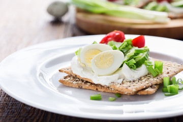Chia seed crackers with cream cheese, cucumbers, tomato, quail egg and green onion
