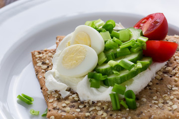 Chia seed crackers with cream cheese, cucumber, tomato, quail egg and green onion