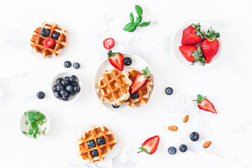 Belgian waffles with fresh strawberry and blueberry on white background. Flat lay, top view, copy space