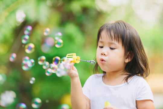 Outdoors activity : Cute kid blowing bubbles soap in the  garden. Picture for concept of childhood in school age.