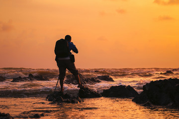 Silhouette of young photographer on the beach