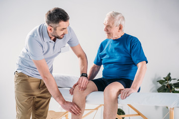 portrait of rehabilitation therapist doing massage to senior man on massage table
