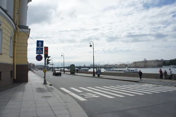 Road with cars, pedestrian crossing, road signs along the embankment. Urban town