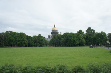 Park in front of famous Isaac cathedral in Saint Petersburg, Russia. Natural lawn showing a wide field of green grass, with trees and domes in the background.