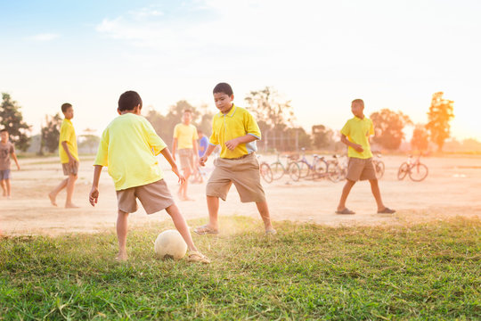 An action picture of a group of kids playing soccer football for exercise in community rural area.
