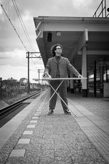 Man ironing his suit in the city on the platform of a train station