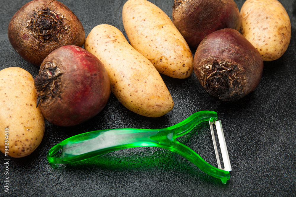 Wall mural Roots of potatoes and red beets with vegetable peelings.