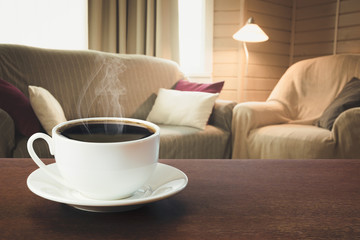 Fototapeta na wymiar Hot coffee on tabletop in modern living room in rustic style with chair, soft divan.