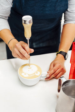 Woman drawing a bear face with milk in the surface of a cup of coffee in Bogota, Colombia