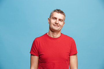 Fototapeta premium The happy business man standing and smiling against blue background.
