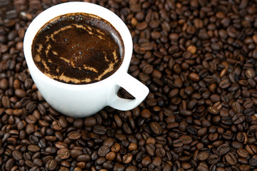 Cup of coffee on the coffee beans background.