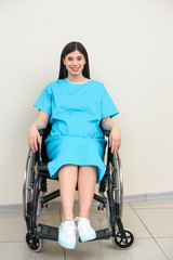 Fototapeta na wymiar happy pregnant woman in medical coat sitting on wheelchair