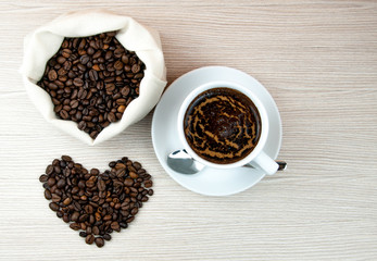 Cup of coffee.Coffee beans heart on the wooden table.
