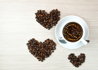 Cup of coffee.Coffee beans heart on the wooden table.