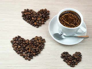 Cup of coffee.Coffee beans heart on the wooden table.