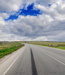 Fototapeta na wymiar asphalt road with brake track and low clouds