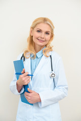 Fototapeta premium happy female doctor with clipboard on white