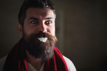 Handsome young bearded man is brushing teeth with toothbrush and surprised looking at his...