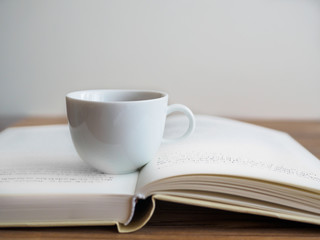 Nahaufnahme auf eine weiße Tasse auf einem offenen Buch