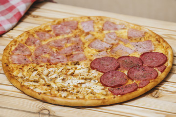 Italian pizza with four types of meat on a wooden table tasty and appetizing