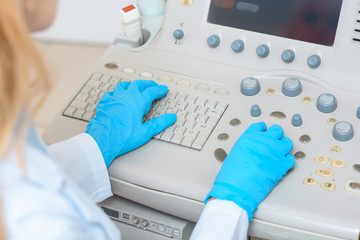 cropped shot of female obstetrician gynecologist in gloves working with ultrasonic scanner