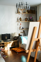Artistic equipment: artist paper or canvas on easel in an artist studio. Cozy room of creative people. Vertical photo