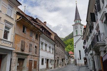 Street A small town in the mountains of Slovenia, Europe. Shabby old houses facades, and roofs. Center of the city and the Catholic Church