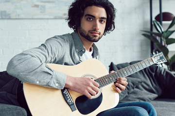 handsome guitarist looking at camera at home