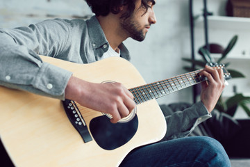 handsome guitarist playing acoustic guitar at home