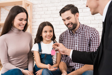 Happy young family gets keys to new house, which realtor helped to choose. Family buys house.