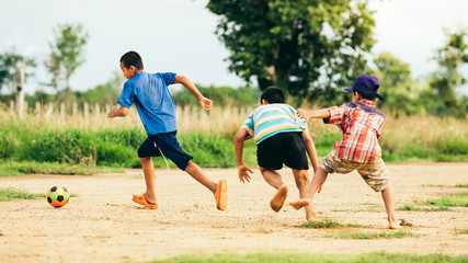 An action sport picture of a group of kid playing soccer football for exercise in community rural...