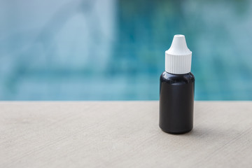 Black plastic bottle over blurred blue swimming pool background