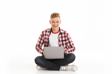 Smiling young guy using laptop computer