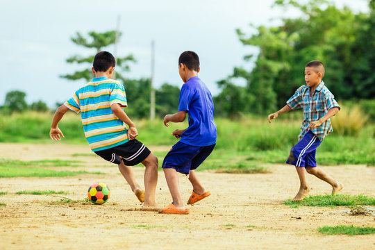 An action sport picture of a group of kid playing soccer football for exercise in community rural area 