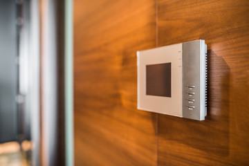 Video intercom display on wooden wall near the entrance door