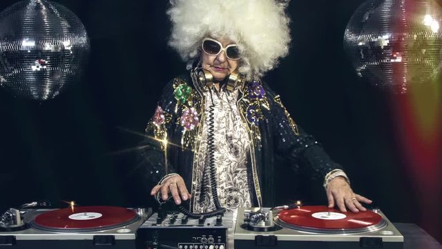 amazing DJ grandma scratching vinyl, older lady djing and partying in a disco setting. these retired rockers will get the party going.
