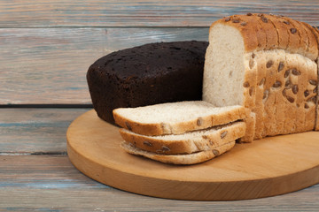 Many mixed breads and rolls of baked bread on wooden table background.