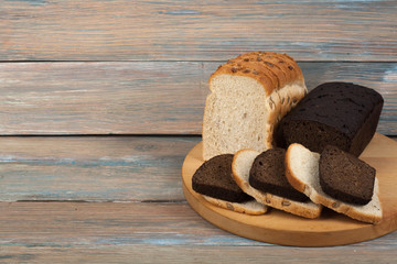 Many mixed breads and rolls of baked bread on wooden table background.