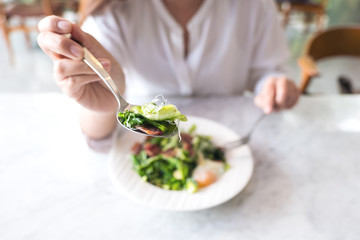 A woman scooping warm salad with spoon before eating on table in the restaurant