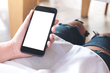Mockup image of woman's hand holding black mobile phone with blank white desktop screen in cafe