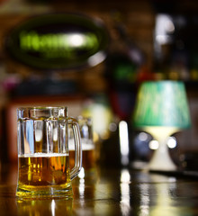 Glass of draft beer on blurred bar background, close up.