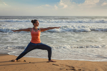 Fototapeta na wymiar Woman doing yoga asana Virabhadrasana 1 Warrior Pose on beach on
