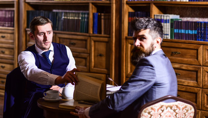 Men in suit with antique bookshelves on background.