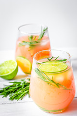 glass of fresh juice with lime and rosemary on white table backg