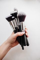 Brushes for make-up in hands.