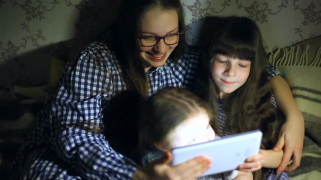 Mother and children with a tablet computer at home watching cartoons and playing