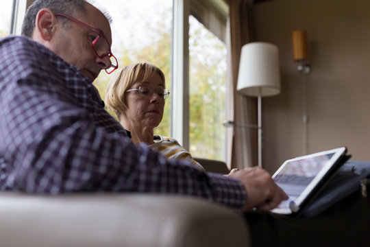Snior couple using tablet computer while sitting on sofa.