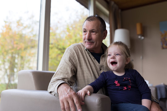 Grandfather and daughter sitting in sofa together