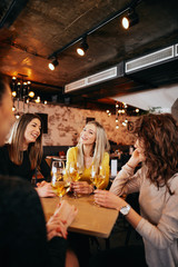 Girlfriends drinking wine and chatting while sitting in the bar.