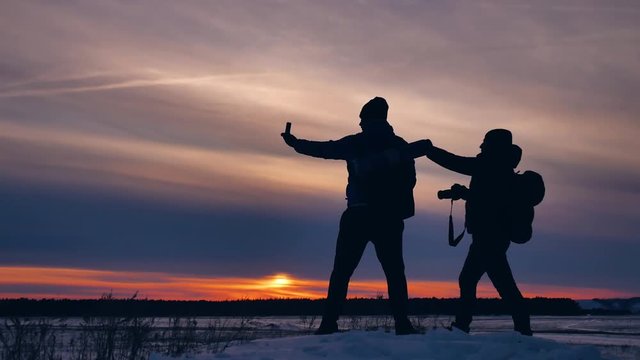 two tourists happy silhouette photograph nature travel at sunset climb the mountain experience the joy .winter trip travel men with backpacks silhouette sunny light sunset